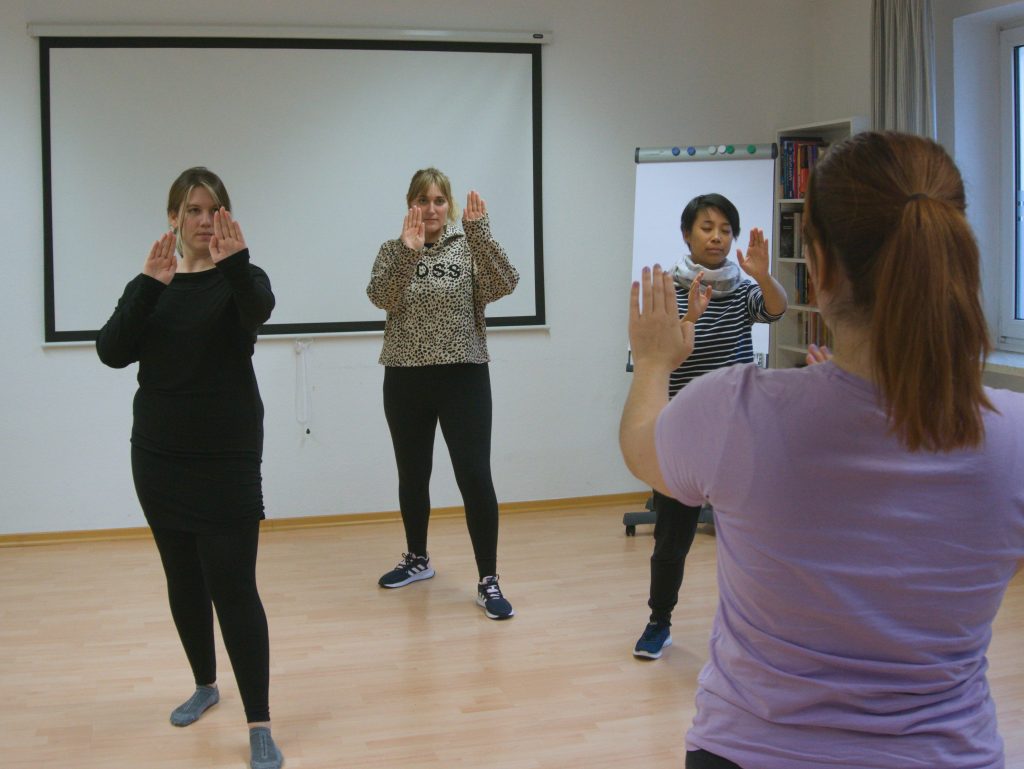 Drei Frauen und die Trainerin üben in einem Selbstverteidigungskurs abwehrende Haltungen und Techniken